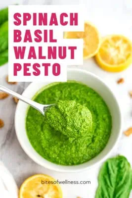 Bowl filled with spinach basil walnut pesto, spoon in the bowl.