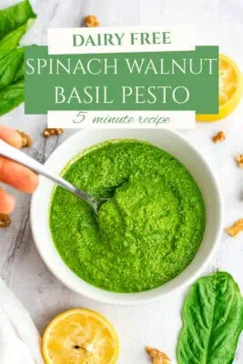 Bowl filled with spinach basil walnut pesto, spoon in the bowl.