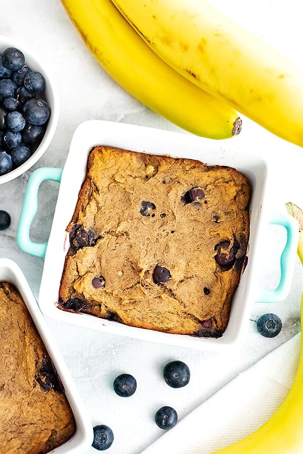 Fork holding a small piece of blueberry banana bread from serving dish