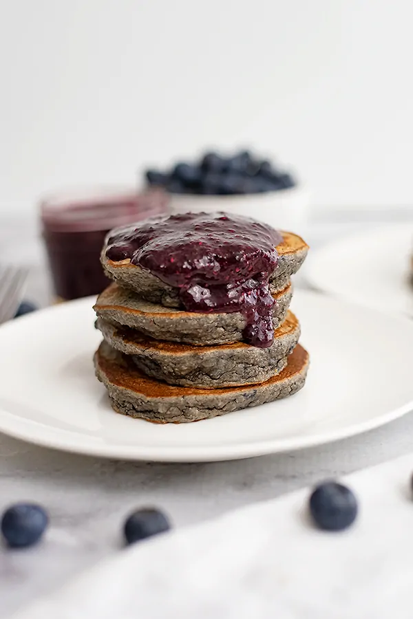 Stack of blueberry protein pancakes with blueberry syrup on top