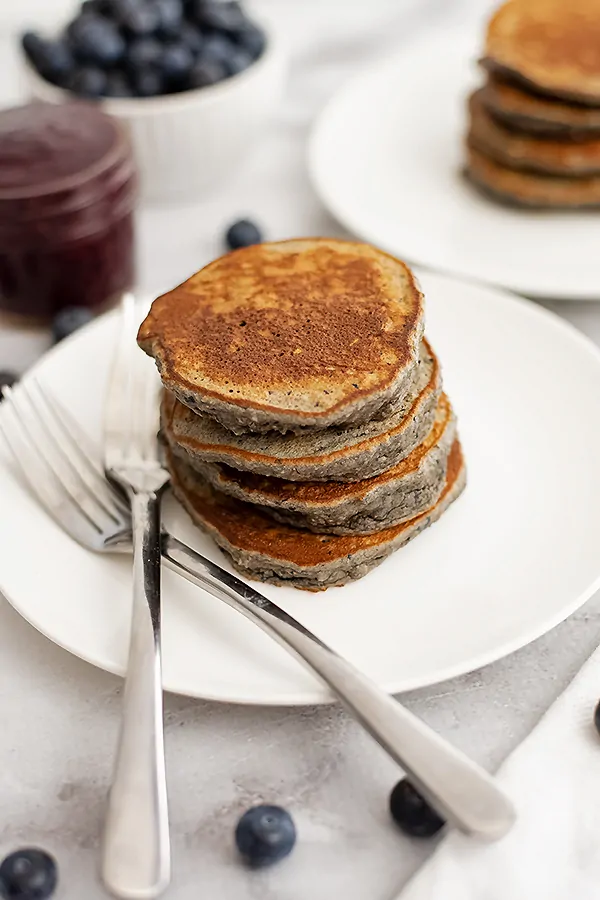Stack of 4 blueberry pancakes with 2 forks next to the pancakes