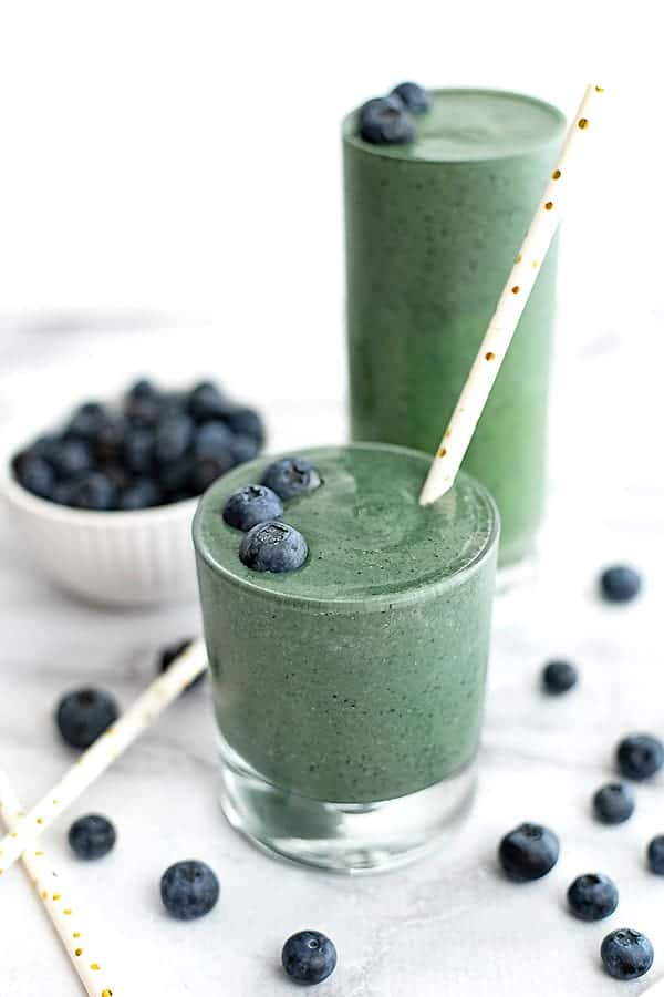 blueberry smoothie in a tall glass with a straw