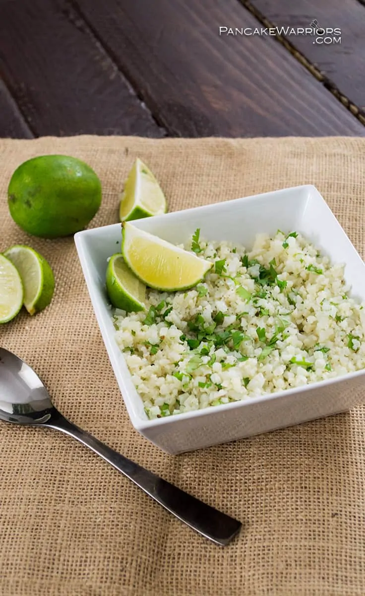 Hand holding a serving spoon in a bowl of cilantro lime cauliflower rice