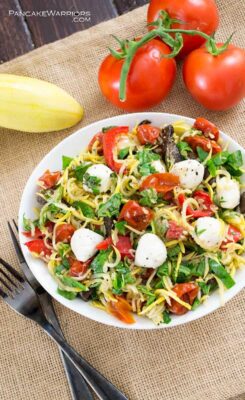 Incredibly easy pasta salad made with summer squash noodles and filled with the favors of margherita pizza - basil, tomato, and fresh mozzarella cheese. This pasta salad is ready in minutes, especially compared to traditional pasta salad! Naturally gluten free,low carb and super filling without any of the guilt!| www.pancakewarriors.com