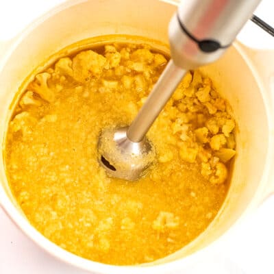 Immersion blender blending cauliflower in pot.