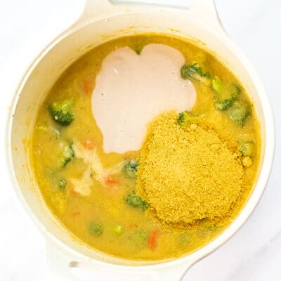 Dairy free milk and nutritional yeast being added to broccoli soup base.