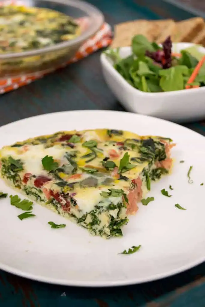Slice of smoked salmon frittata on a white plate. 