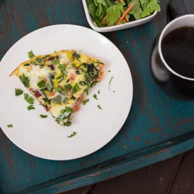 Smoked salmon frittata on a white plate resting on a teal serving tray.