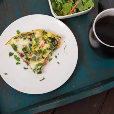 Smoked salmon frittata on a white plate resting on a teal serving tray.