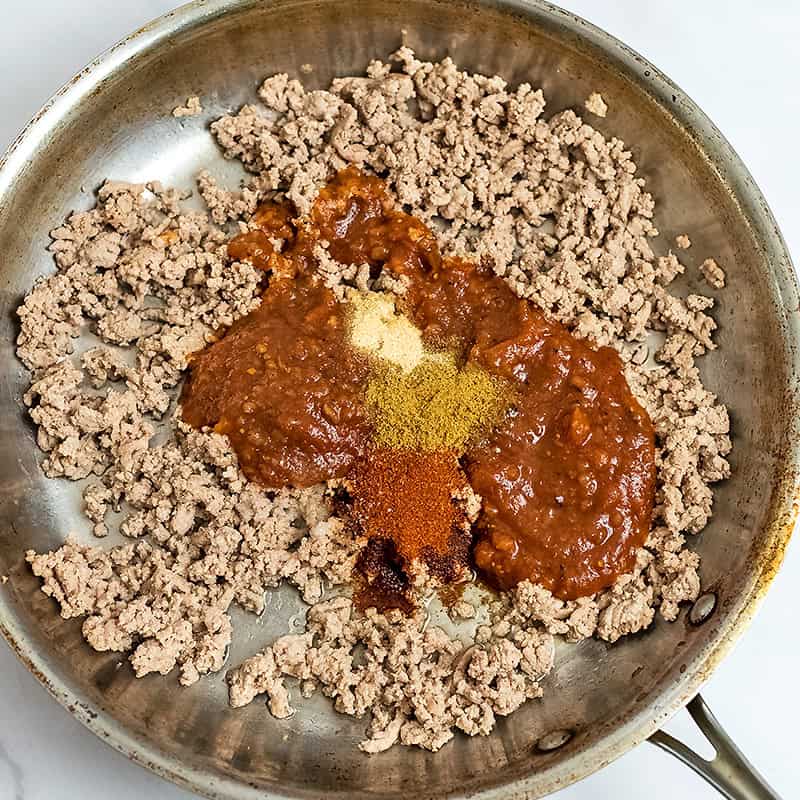 Ground turkey, spices and salsa in a skillet before combining the ingredients.