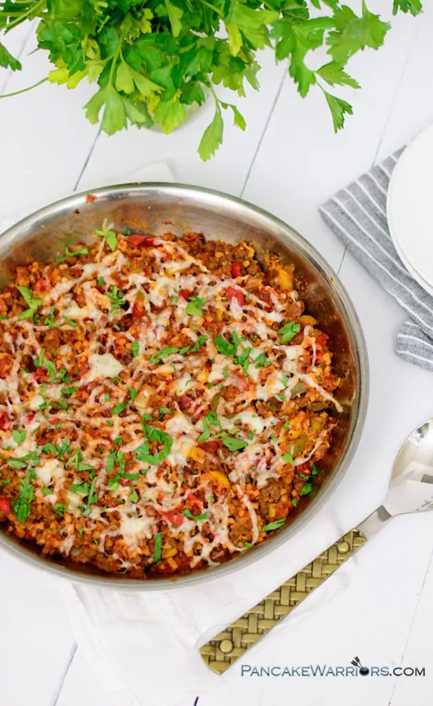 simple low carb cauliflower lasagna in a skillet with a large serving spoon