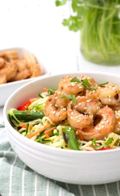 Bowl filled with ginger garlic shrimp zoodle bowl over a blue striped napkin