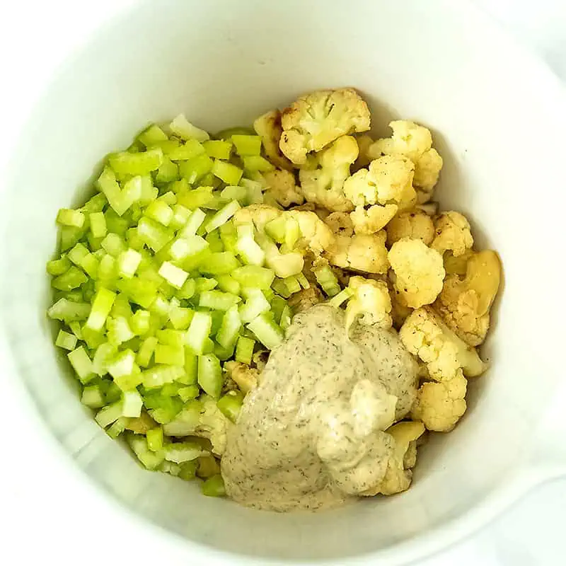 Cauliflower, celery, and tahini dressing in a bowl.