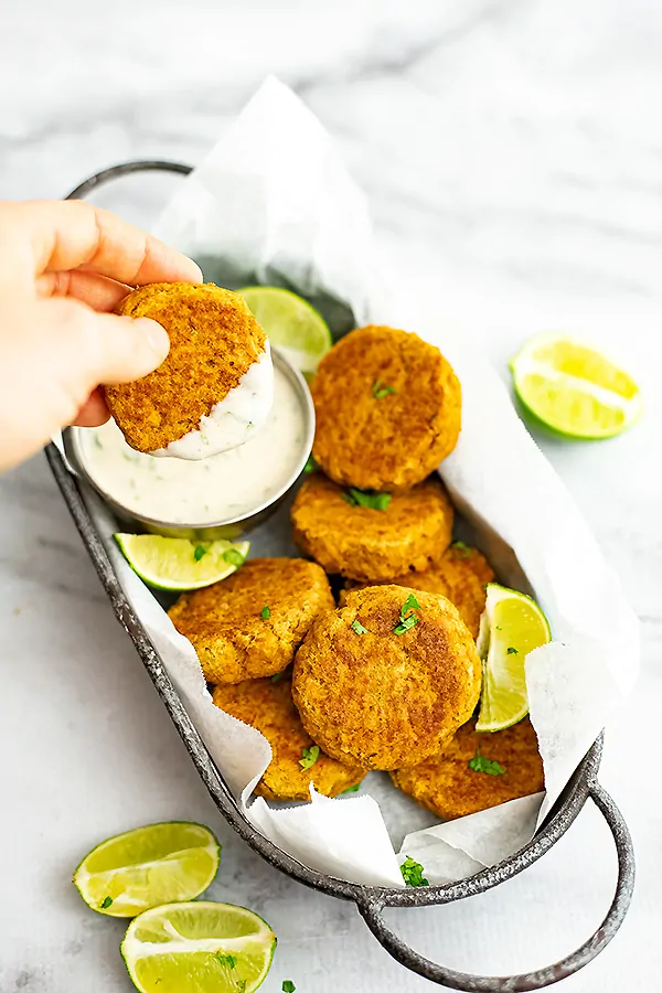 Curry salmon cake being dipped in cilantro lime yogurt dip