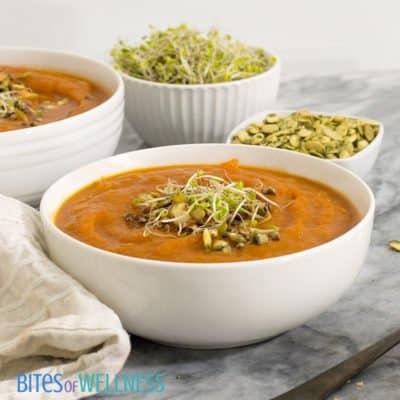 Two bowls of slow cooker curried butternut squash soup with sprouts and pumpkin seeds