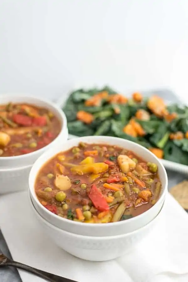 Two bowls of frozen vegetable soup with a salad in background