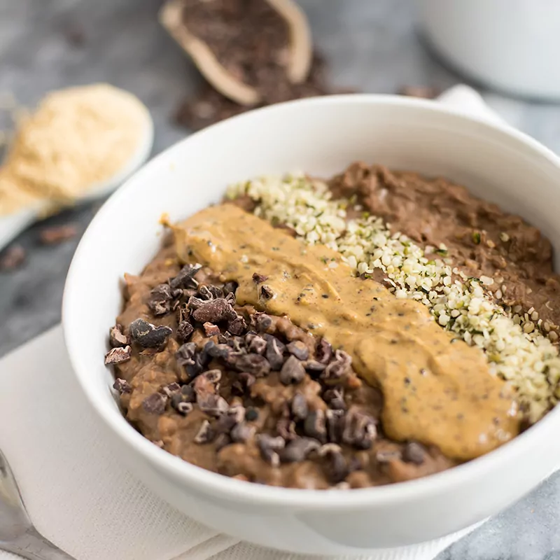 Chocolate Peanut butter Low Carb Oatmeal in a bowl with peanut butter, cocoa nibs and hemp hearts on top