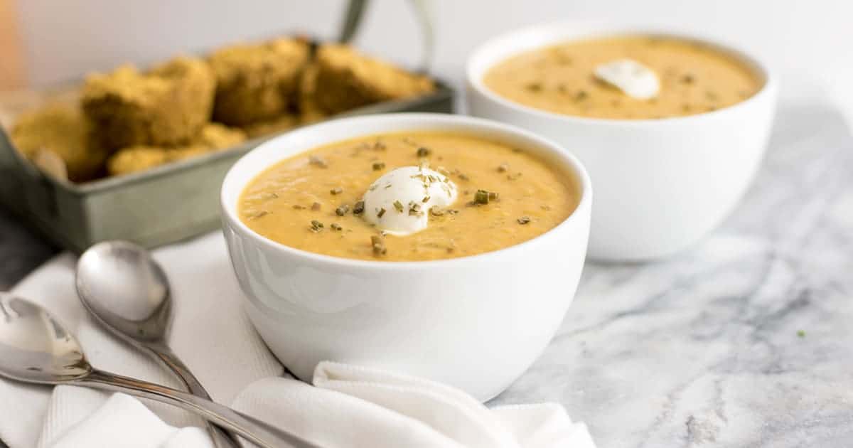  Roasted vegetable bisque in a bowl with nut cheese topping and cornbread muffins