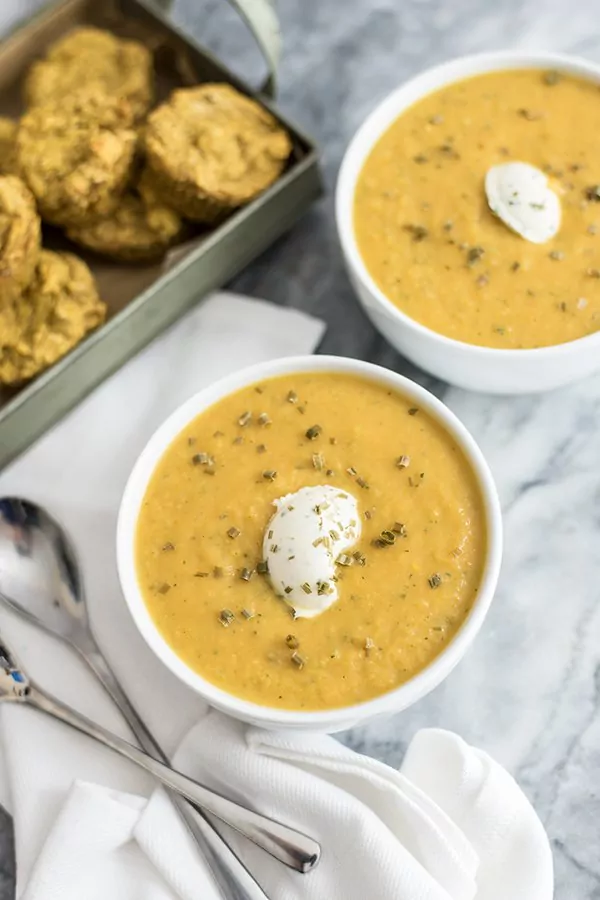 Roasted vegetable bisque in a bowl with nut cheese topping and cornbread muffins