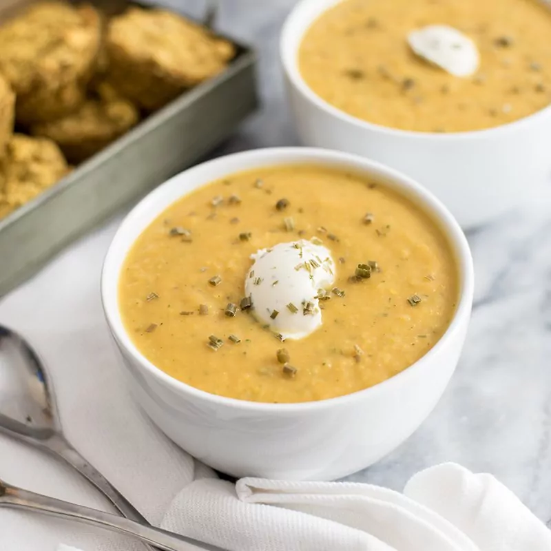  Roasted vegetable bisque in a bowl with nut cheese topping and cornbread muffins