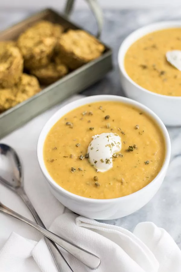  Roasted vegetable bisque in a bowl with nut cheese topping and cornbread muffins