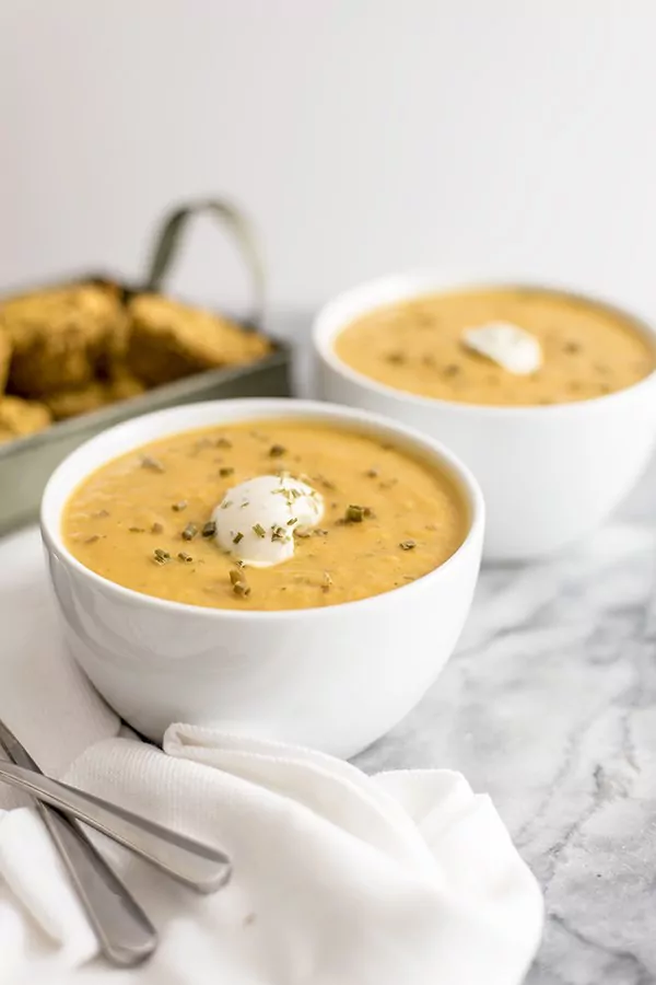  Roasted vegetable bisque in a bowl with nut cheese topping and cornbread muffins