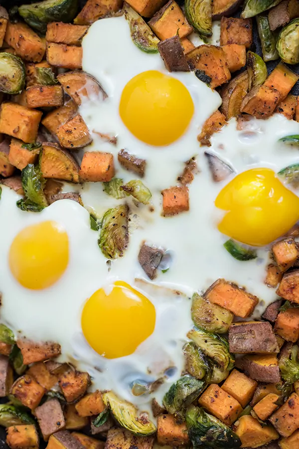 Close up picture sweet potato breakfast hash with brussels sprouts and eggs in an iron skillet