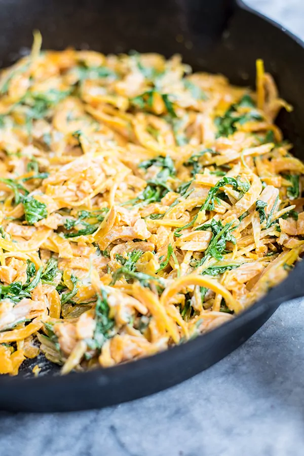 butternut squash noodles with a creamy garlic sauce with arugula in a cast iron skillet