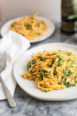 butternut squash noodles with a creamy garlic sauce with arugula on white plate with fork