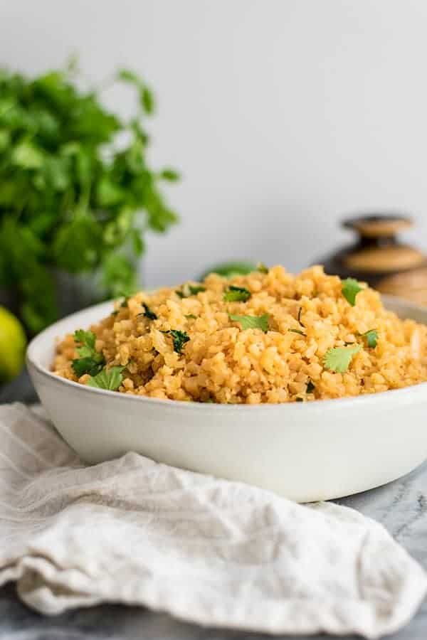 Whole30 Mexican cauliflower rice topped with chopped cilantro over a grey napkin