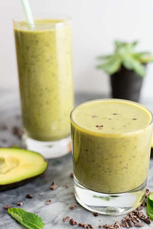 Mint chocolate protein shake in short glass in front and large glass behind. mint and avocado