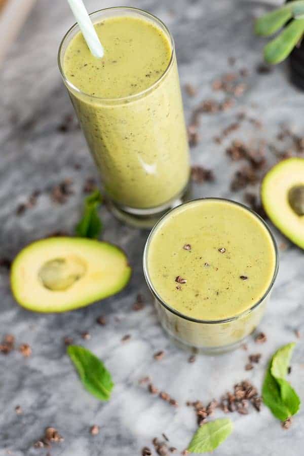 Mint chocolate protein shake in short glass in front and large glass behind. mint and avocado