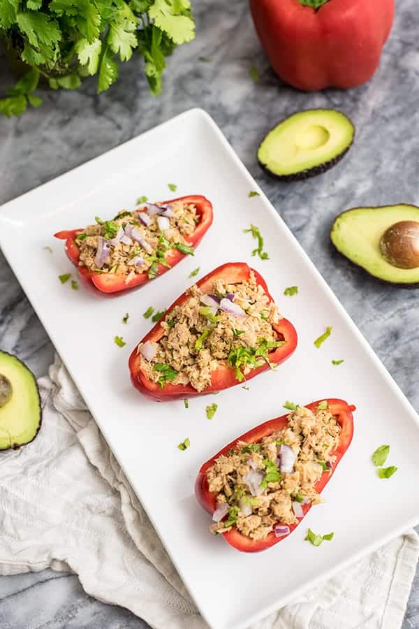 Tuna Stuffed Peppers on a white serving tray with avocado, red bell pepper and cilantro