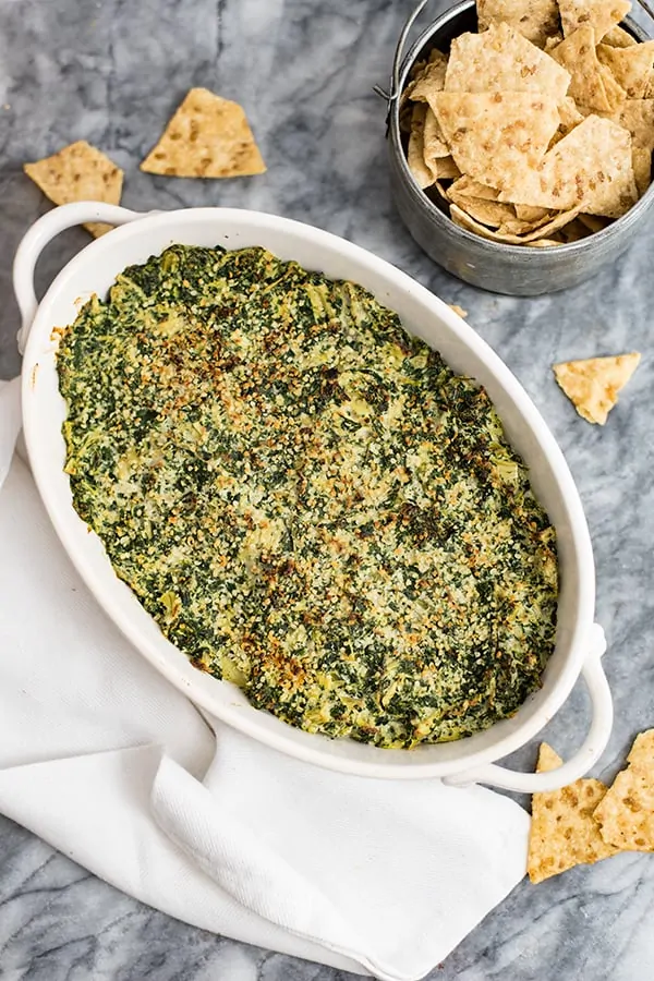 Spinach Artichoke Dip in a white casserole dish with chips