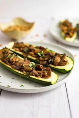 Two stuffed zucchin on an off white plate