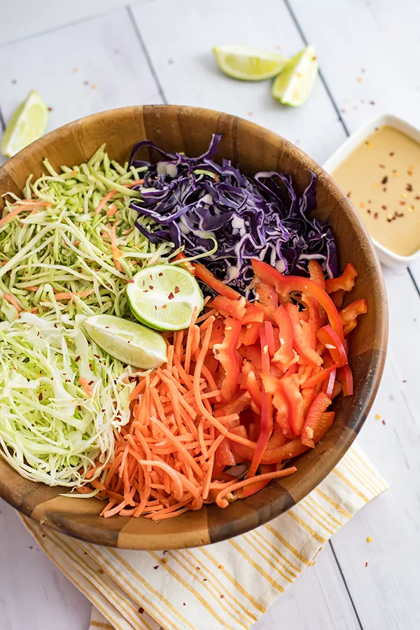 Large wooden bowl of veggies before tossing to make the spicy creamy asian slaw recipe