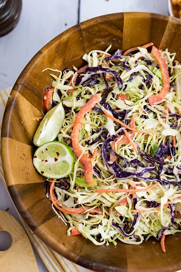 Overhead shot of Large wooden salad bowl filled with spicy creamy asian slaw
