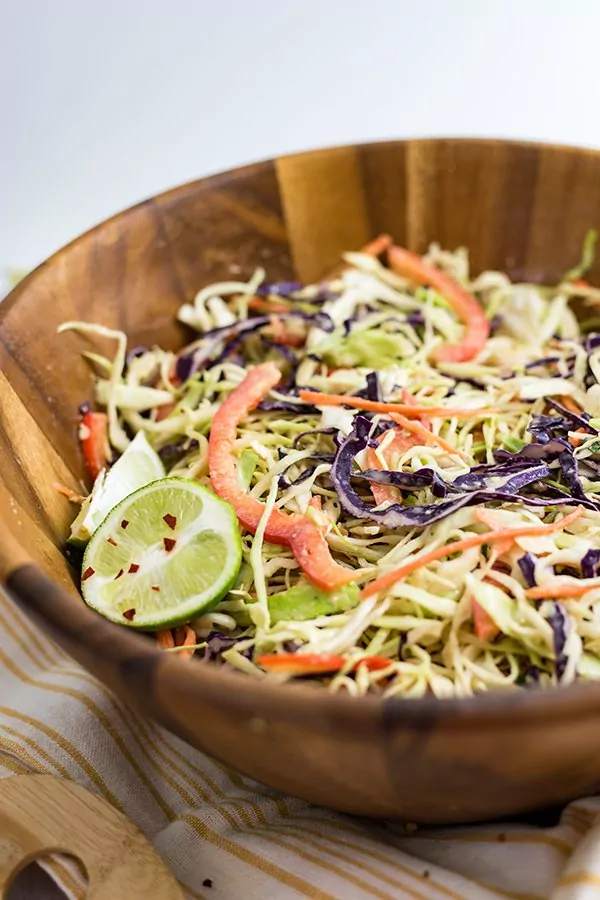 Large wooden salad bowl filled with spicy creamy asian slaw