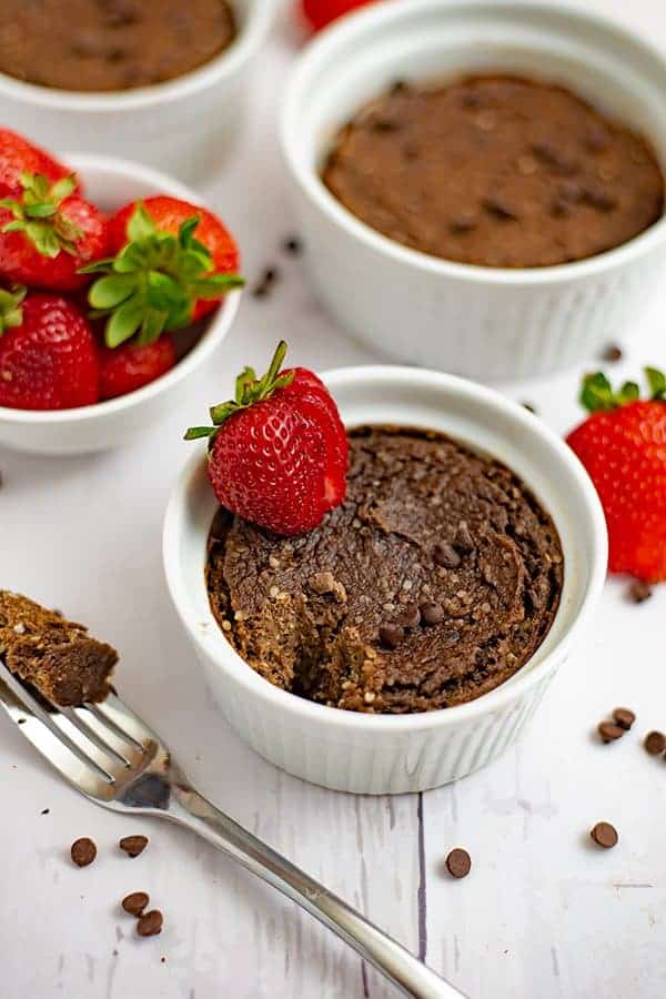 White ramekin with a single serve brownie with a fork full of brownie on the side