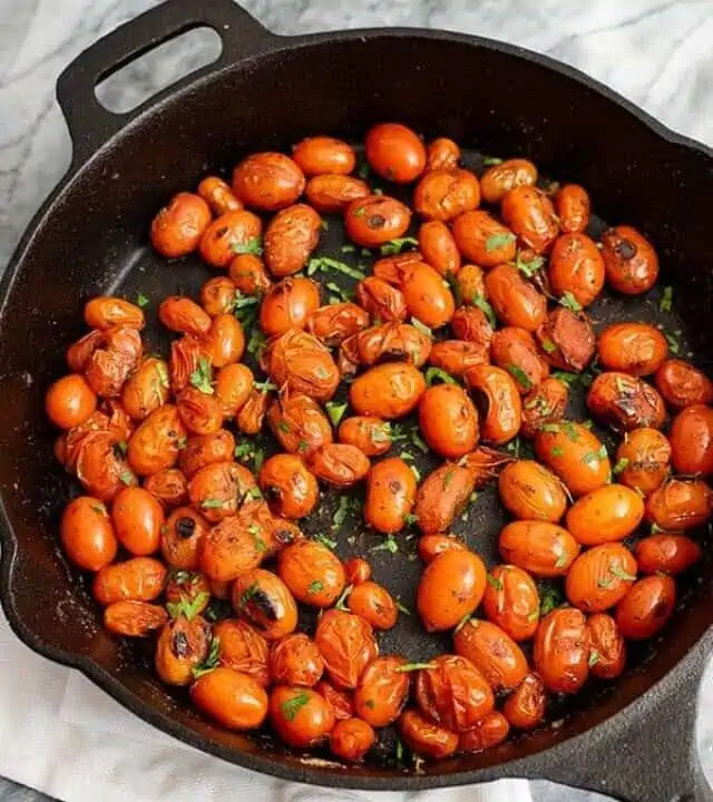 Overhead shot of a cast iron skillet filled with blistered tomatoes