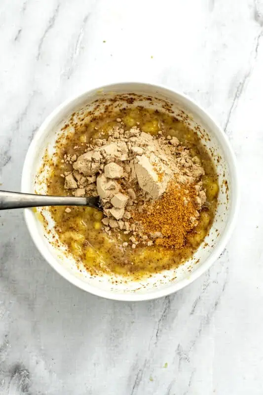 Chocolate protein powder and cacao powder added to banana mixture