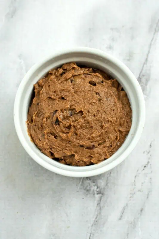 Brownie batter added to ramekin before baking.