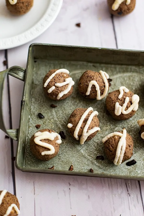 Close up of Mocha quinoa energy bites with coconut frosting over a green tray 