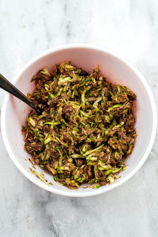 Shredded zucchini added to bowl with mashed black beans.