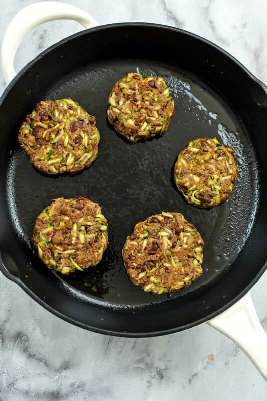 Black bean zucchini burgers in a cast iron skillet before cooking.