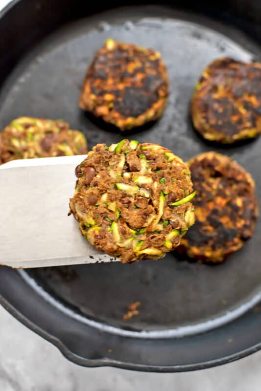 Zucchini black bean burger being flipped.