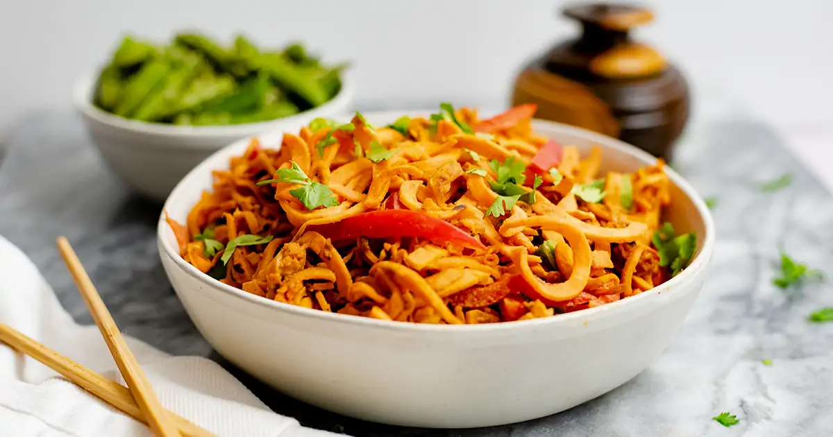 Close up shot of spicy peanut spiralized sweet potatoes in a large white bowl. 