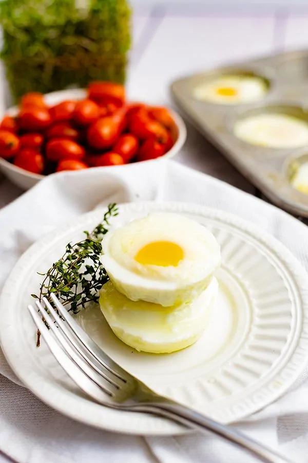 Two perfectly poached eggs stacked on top of each other on plate