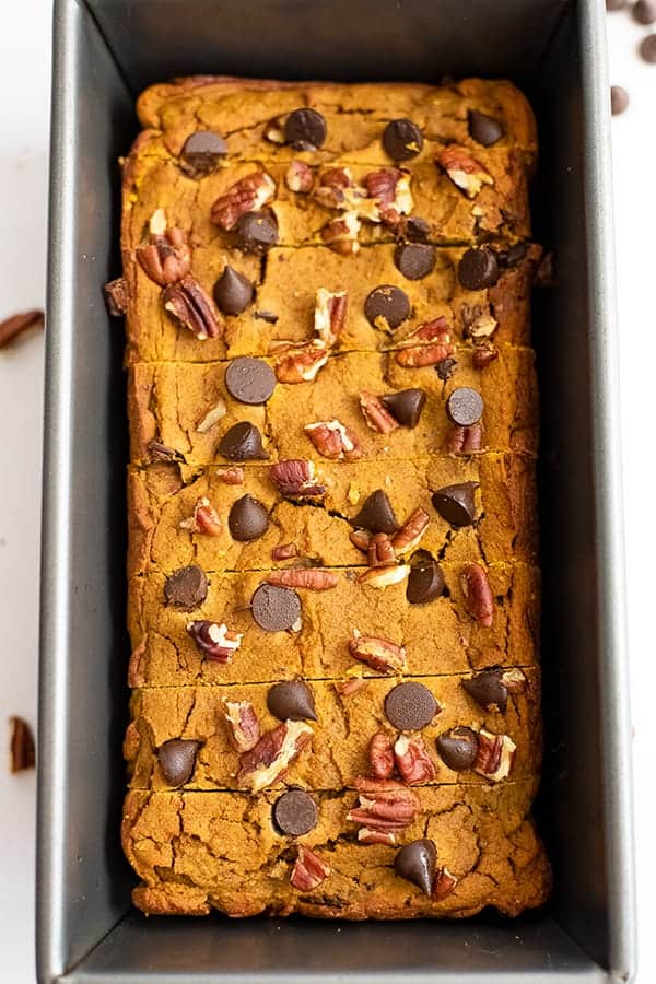 Loaf pan filled with healthy pumpkin bread recipe topped with chocolate chips and pecans
