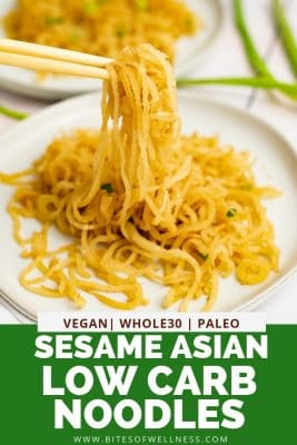 White plate filled with sesame Asian low carb noodles with chopsticks picking up the noodles, bringing the noodles into focus with pinterest text on the bottom